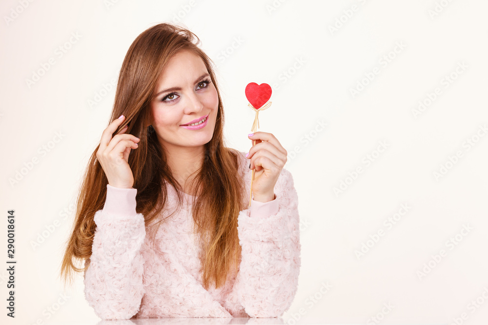Flirty woman holding red wooden heart on stick Flirty woman holding red wooden heart on stick