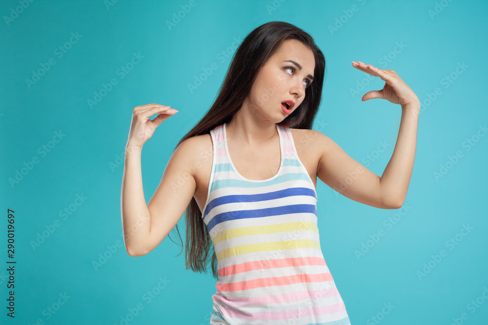 Brunette woman with long hair, dressed in colorful striped shirt, posing against blue studio background. Sincere emotions. Close-up. Brunette woman with long hair, dressed in colorful striped shirt, posing against blue studio background. Sincere emotions. Close-up.