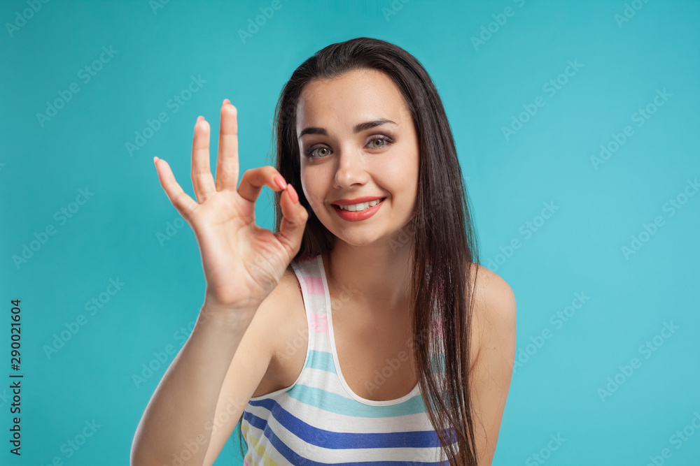 Brunette woman with long hair, dressed in colorful striped shirt, posing against blue studio background. Sincere emotions. Close-up. Brunette woman with long hair, dressed in colorful striped shirt, posing against blue studio background. Sincere emotions. Close-up.