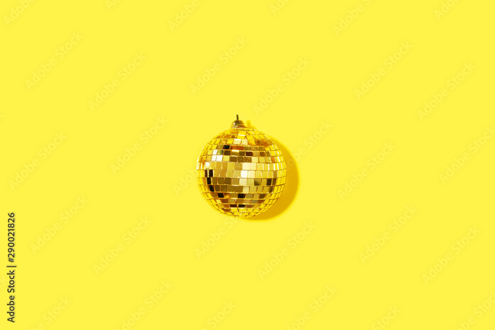 Creative Christmas composition. Flat lay, top view. Disco ball bauble on yellow background with copy space. Minimal New year party concept. Minimal Christmas gold decoration