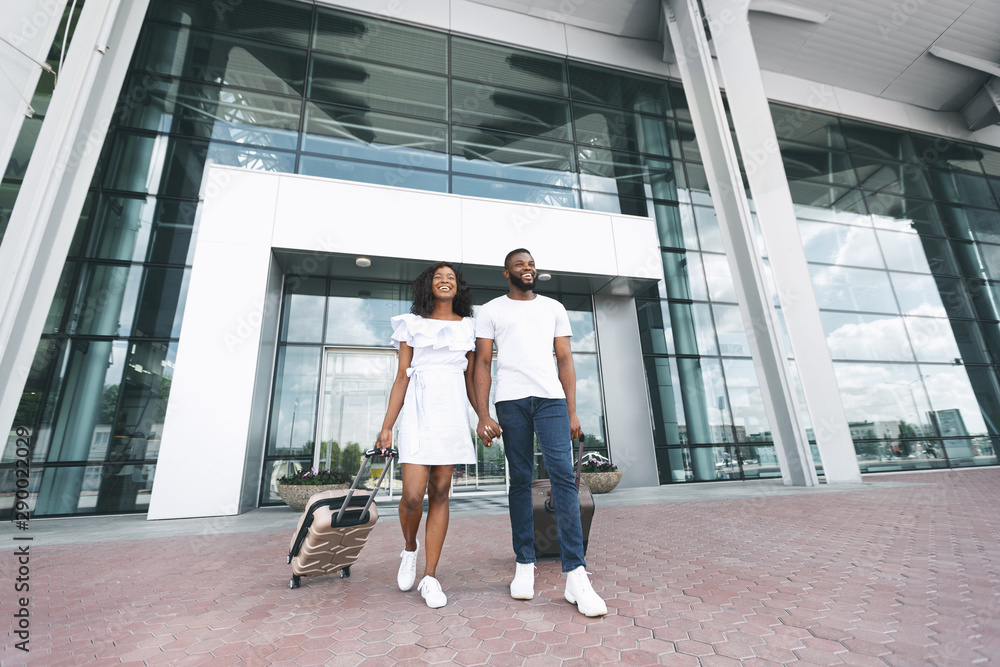 Happy millennial black couple enjoying new destination at airport building