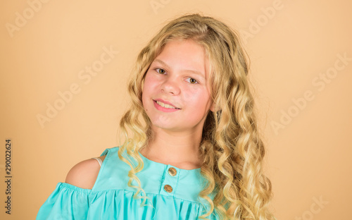 hair health and care. hairdresser salon. beauty and fashion. long blond curly hair. beautiful little girl fashion model. happy little girl with long healthy hair. Facial care