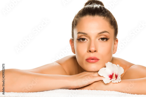 Sensual portrait of a young beautiful woman with bun, lying on a white background