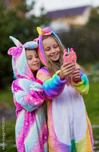 Girlfriends in unicorn costumes. Party unicorns. Two girlfriends take a selfie on the phone.