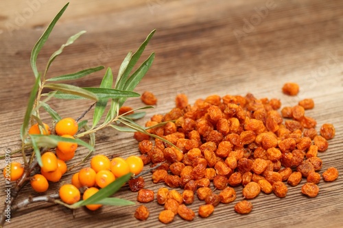 Dried and fresh sea buckthorn berries, Hippophae rhamnoides. Brown table in rustic style with common  sea  buckthorn. photo