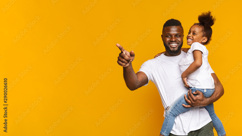 Cheerful african man showing something to his little daughter - obrazy, fototapety, plakaty 