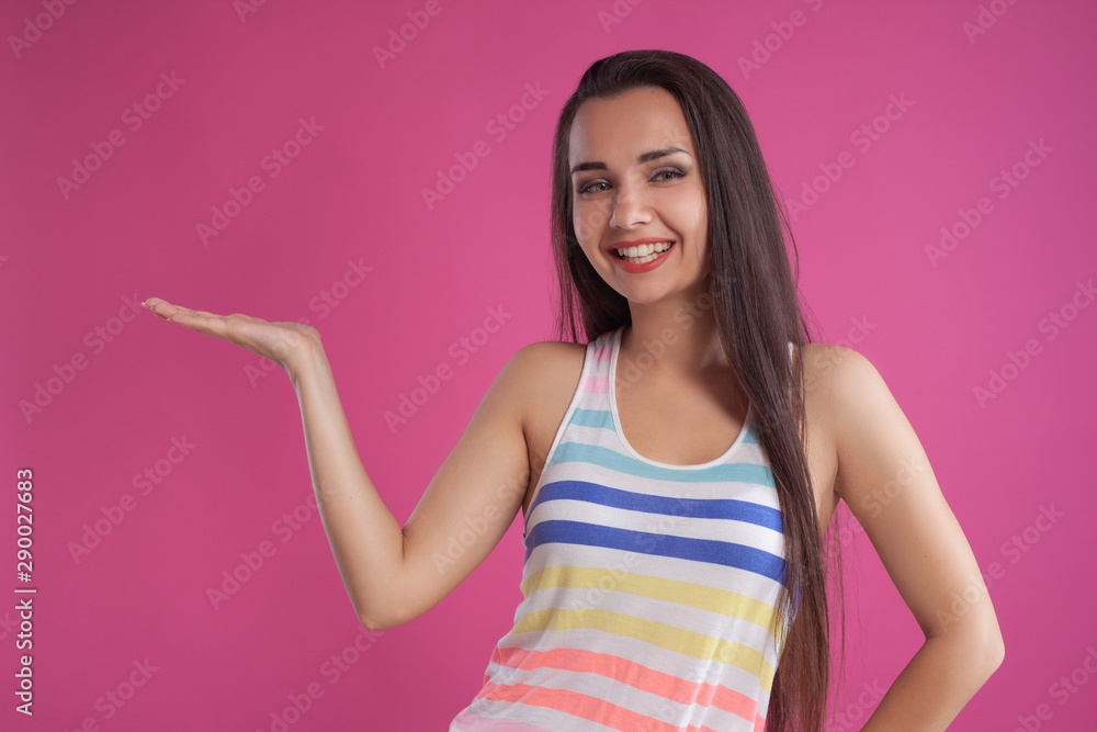 Brunette woman with long hair, dressed in colorful striped shirt, posing against pink studio background. Sincere emotions. Close-up. Brunette woman with long hair, dressed in colorful striped shirt, posing against pink studio background. Sincere emotions. Close-up.