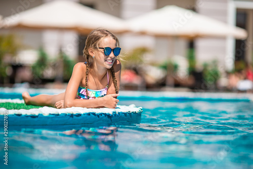 Adorable little girl swimming at outdoor swimming pool