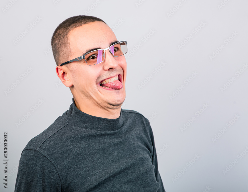 Crazy grimacing man in eye glasses showing the tongue on blue background Crazy grimacing man in eye glasses showing the tongue on blue background