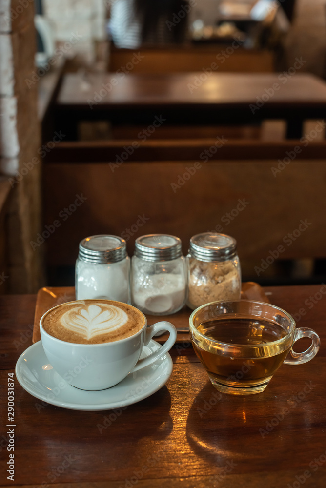 A latte coffee cup is placed at the table, with condiments and tea cups on the side. A latte coffee cup is placed at the table, with condiments and tea cups on the side.