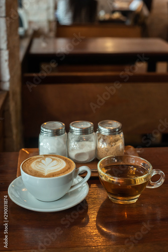 A latte coffee cup is placed at the table, with condiments and tea cups on the side.