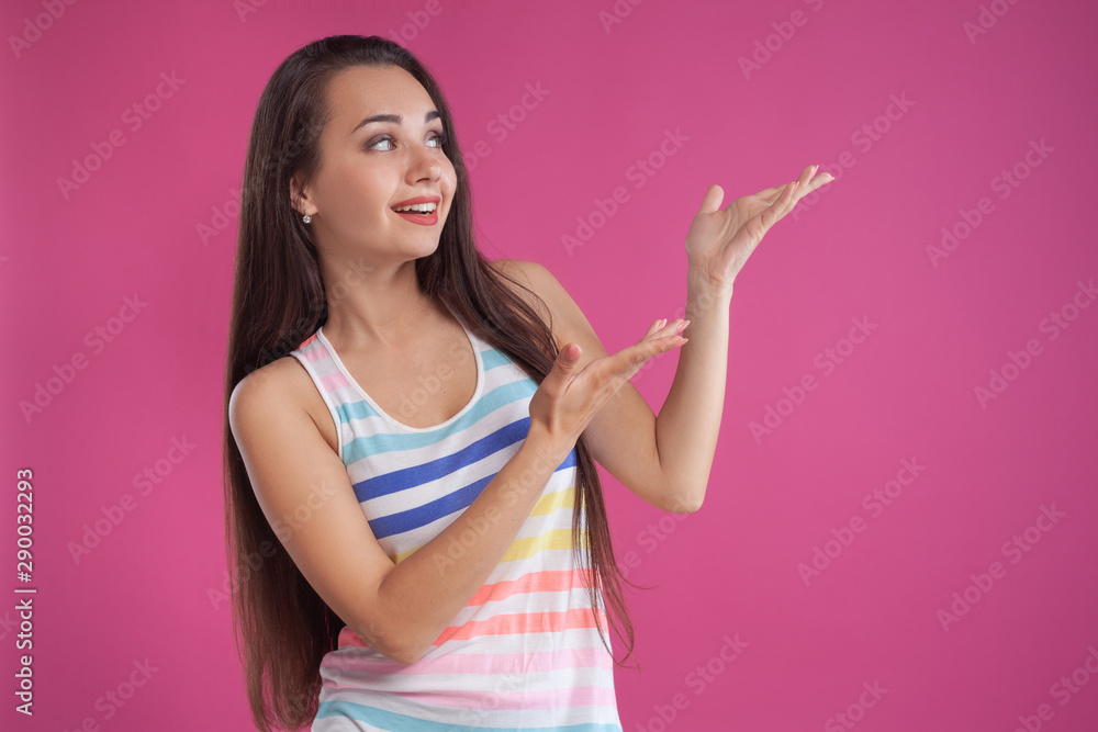 Brunette woman with long hair, dressed in colorful striped shirt, posing against pink studio background. Sincere emotions. Close-up. Brunette woman with long hair, dressed in colorful striped shirt, posing against pink studio background. Sincere emotions. Close-up.