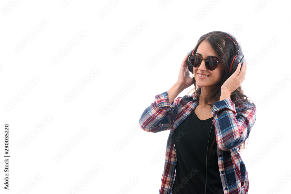 Caucasian young girl with plaid shirt and glasses, listening to music with big headphones and a mobile phone or other type of electronic device on white background isolated Caucasian young girl with plaid shirt and glasses, listening to music with big headphones and a mobile phone or other type of electronic device on white background isolated
