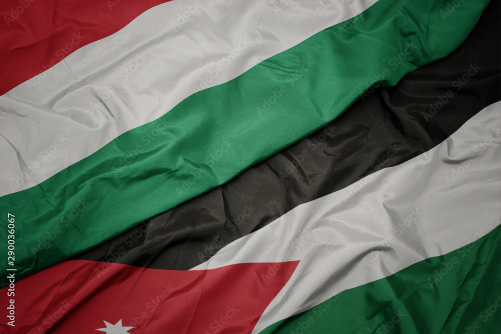 Obraz premium waving colorful flag of jordan and national flag of hungary.