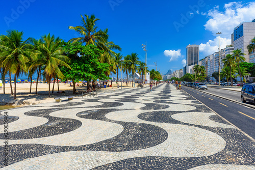 View of Copacabana beach with palms and mosaic of sidewalk in Rio de Janeiro, Brazil. Copacabana beach is the most famous beach in Rio de Janeiro. Sunny cityscape of Rio de Janeiro photo