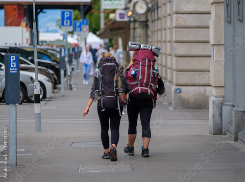 Two female backpackers walking down street in city