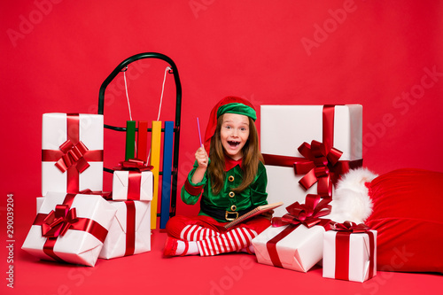 Nice attractive cheerful cheery excited funny funky small little pre-teen elf creating winter holly jolly fairy miracle tradition idea wish list isolated over bright vivid shine red background photo