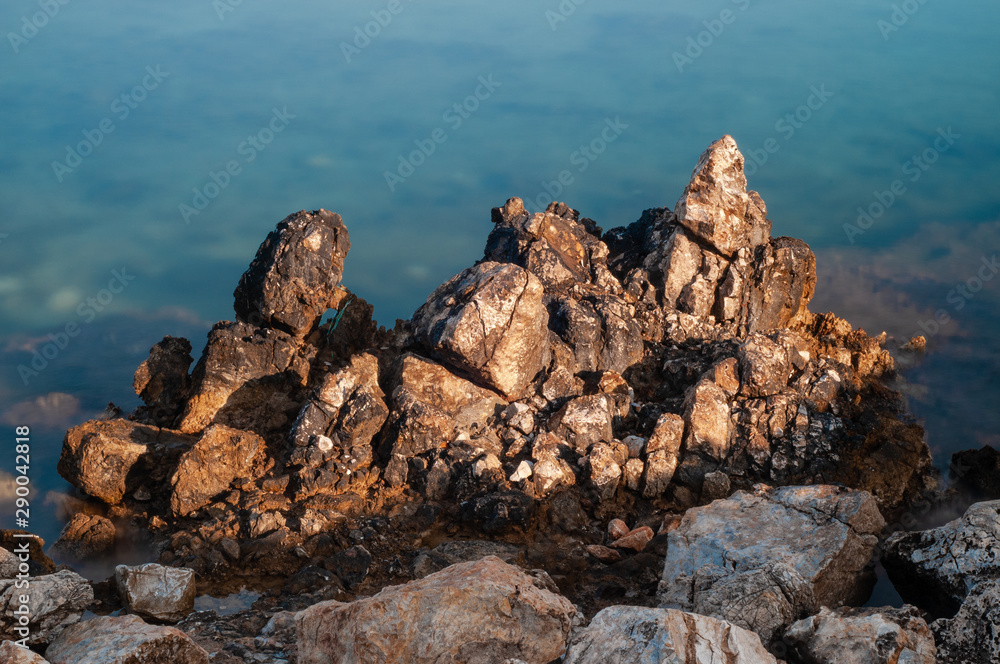 Sharp stones and rocks in the turquoise, blue sea. Beautiful seascape. Aegean coast in Turkey at sunrise. Bodrum. Sharp stones and rocks in the turquoise, blue sea. Beautiful seascape. Aegean coast in Turkey at sunrise. Bodrum.