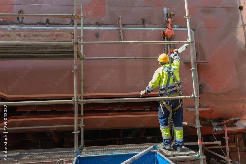 Worker working on ship repairing yard Worker working on ship repairing yard