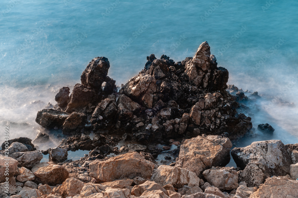 Sharp stones and rocks in the turquoise, blue sea. Beautiful seascape. Aegean coast in Turkey at sunrise. Bodrum.
