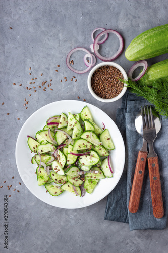 Fresh cucumber salad with flax seeds on gray stone background. Top view.