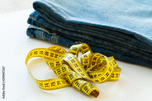 Blue jeans and measuring tape on white background photo