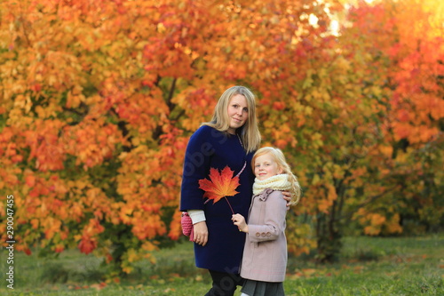 Mom and daughter are walking in the autumn park. Autumn palette