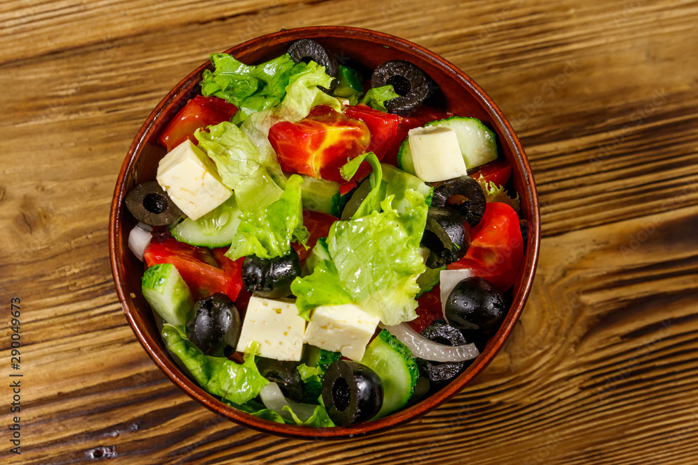 Greek salad with fresh vegetables, feta cheese and black olives on wooden table. Top view
