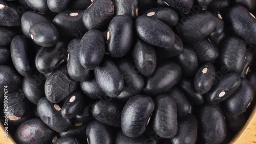 panning black beans in wood bowl isolated on white background. top view