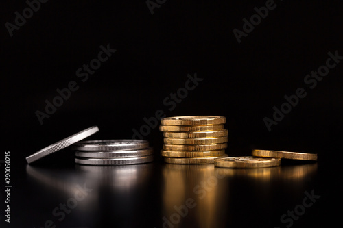 A stack of silver and gold coins. Silver and gold coins on a black background.Coins side view close up. photo