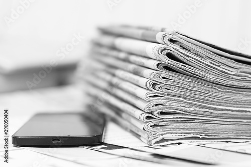 Newspapers amd Smartphone. News Pages with Headlines and Articles and Mobile Phone. Different Sources of Information - Internet or Papers. Concept for Communication 