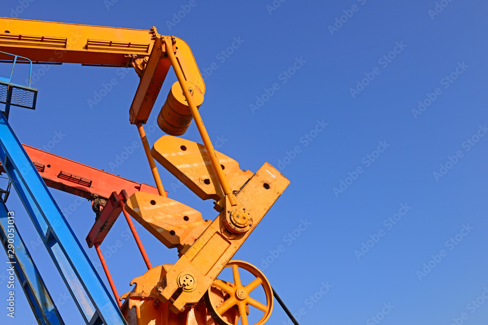 The beam pumping unit is working against the blue sky The beam pumping unit is working against the blue sky