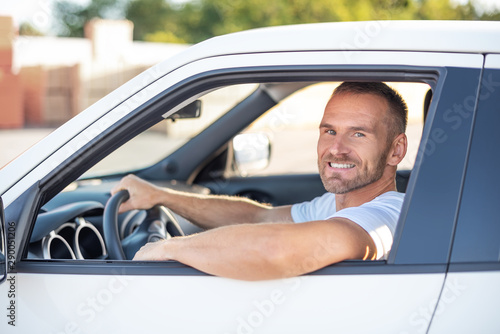 Attractive young man driving a white car.