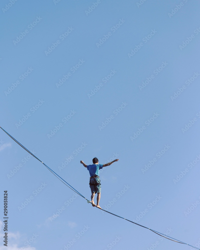 A man is walking along a stretched sling. Highline in the mountains. Man catches balance. Performance of a tightrope walker in nature. Highliner on the background of the mountains. A man is walking along a stretched sling. Highline in the mountains. Man catches balance. Performance of a tightrope walker in nature. Highliner on the background of the mountains.