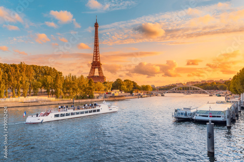 The main attraction of Paris and all of Europe is the Eiffel tower in the rays of the setting sun on the bank of Seine river with cruise tourist ships © EdNurg