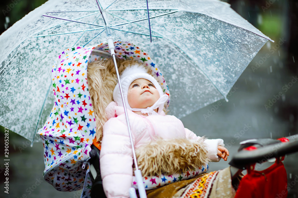 Cute little beautiful baby girl sitting in the pram or stroller on