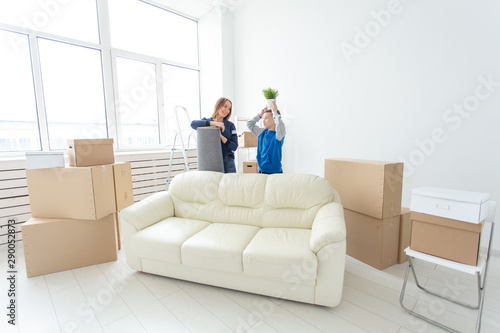 Young cute single mother and son are happy about the move to new house holding a pot of greens and carpet in their hands. Concept of housewarming and family space extensions.