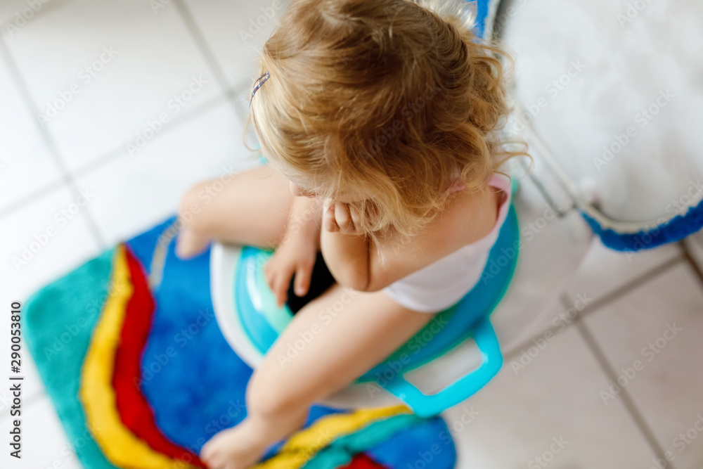 Closeup of cute little toddler baby girl child sitting on toilet wc