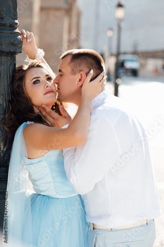 Fashion portrait of young couple in love posing at street. Beautiful girl and handsome boy hugging and kissig outdoors. Fashion photo of elegant stylish couple in love with pleasure.