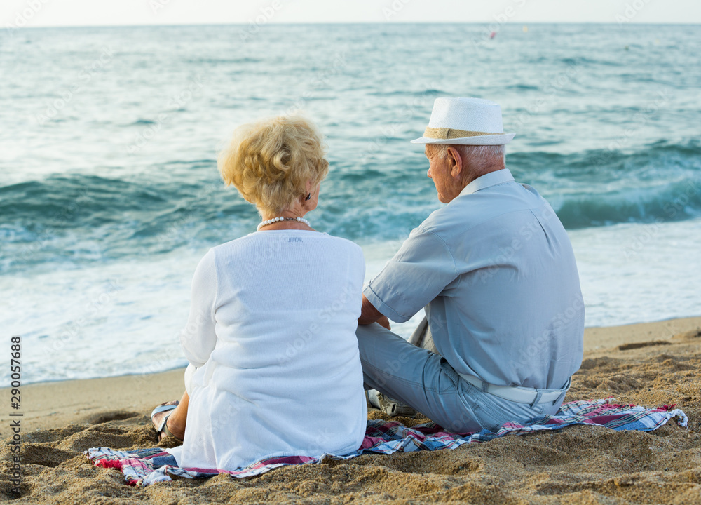 Fototapeta premium female and male in hat sitting on the beach