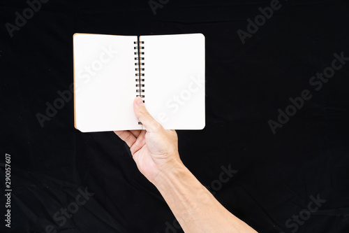 Fototapeta Naklejka Na Ścianę i Meble -  Man hand holding blank notebook on black background