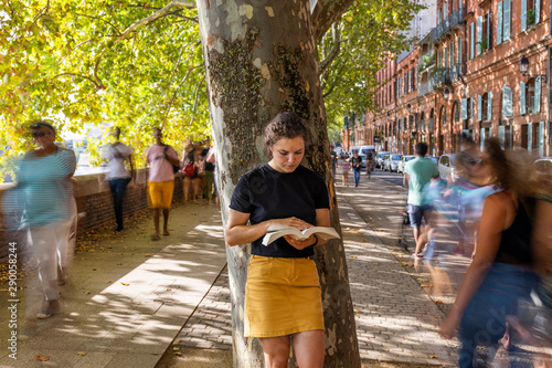 young woman reading in the street 