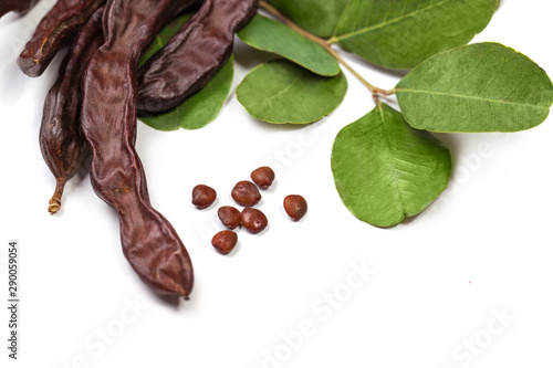 Carob beans. Healthy organic sweet carob pods with seeds and leaves on white background