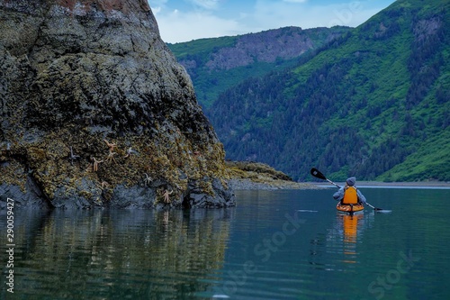 Single kayaker in orange kayak with starfish, Sadie Cove, Alaska