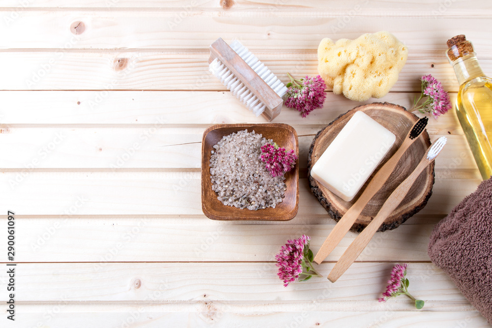 Zero waste bathroom accessories, natural brush, oil, sea salt, hair brash, toothbrush, towel on wooden background Zero waste bathroom accessories, natural brush, oil, sea salt, hair brash, toothbrush, towel on wooden background