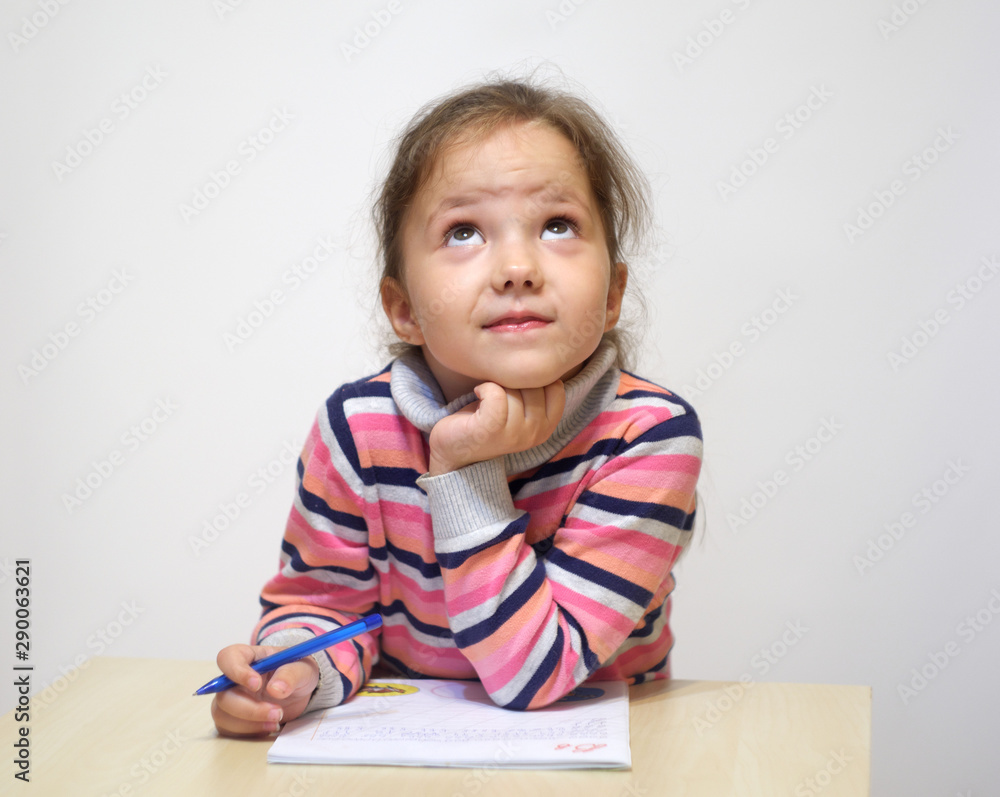 The adorable little girl doing homework and dreams. The adorable little girl doing homework and dreams.