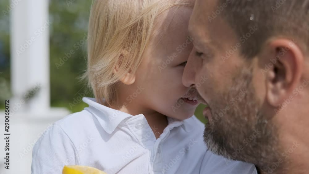 Father and little son look at each other with love. A man holds a child in his arms. close-up Father and little son look at each other with love. A man holds a child in his arms. close-up