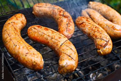 Appetizing grilled bavarian sausages on grate during cooking.