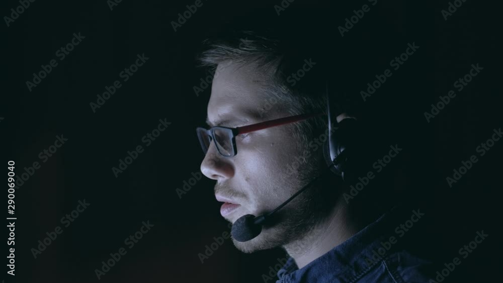 Man from technical support talking using headset in the evening. Remote working from home concept. Man from technical support talking using headset in the evening. Remote working from home concept.