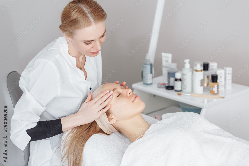Unknown masseuse beautician doing a face massage to her client a beautiful young woman. Skin care concept